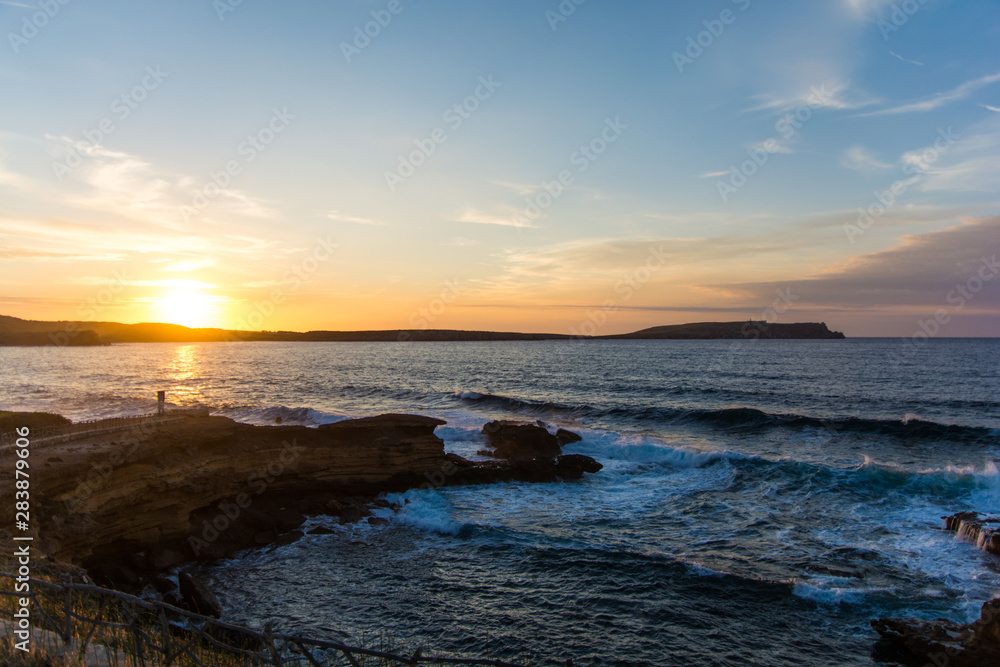 Waves crashing into the rocks and a beautiful sunset.