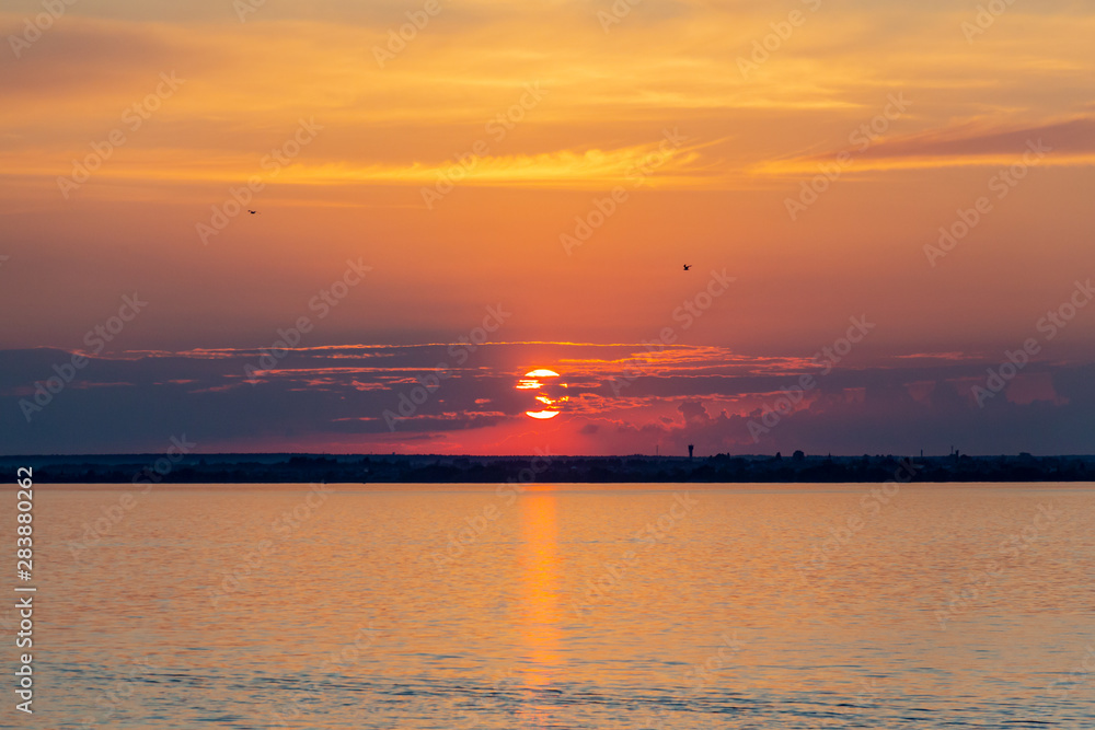 Sunset on the Volga river in Russia in July. Orange sun in the sky. Picturesque nature. Summer evening. River cruise