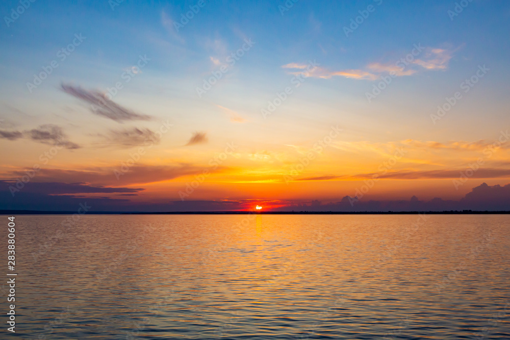 Fototapeta premium Sunset on the Volga river in Russia in July. Orange sun in the sky. Picturesque nature. Summer evening. River cruise