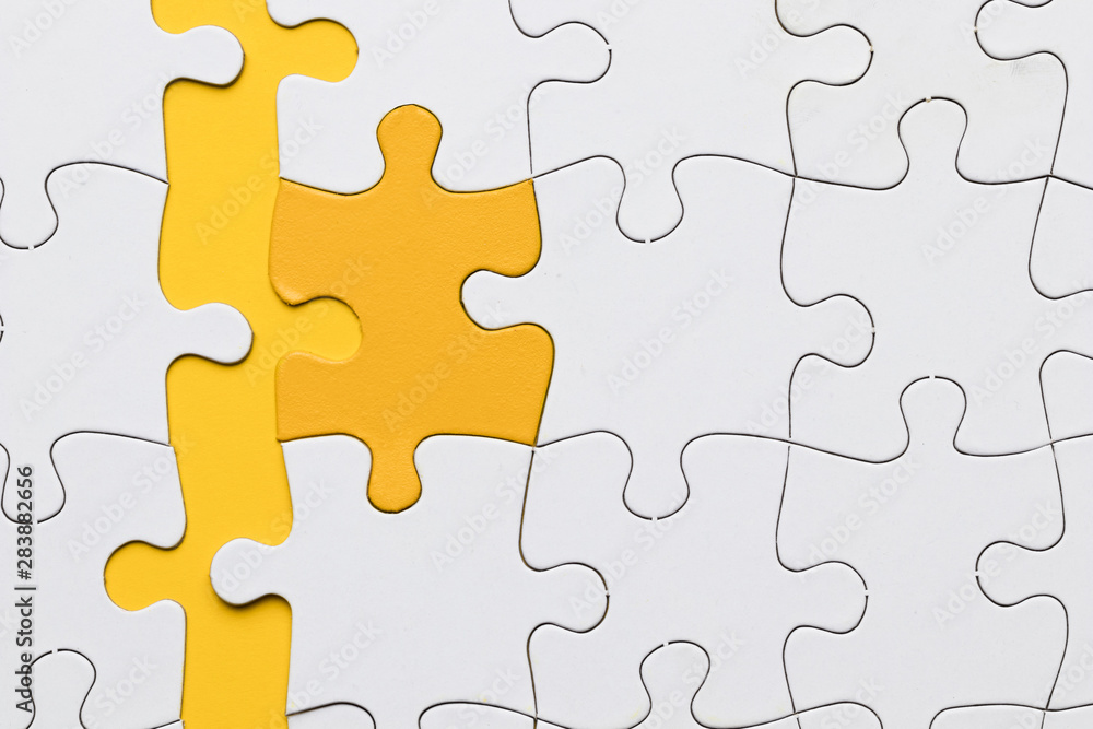 High angle view of yellow puzzle piece arranged with white pieces High angle view of yellow puzzle piece arranged with white pieces