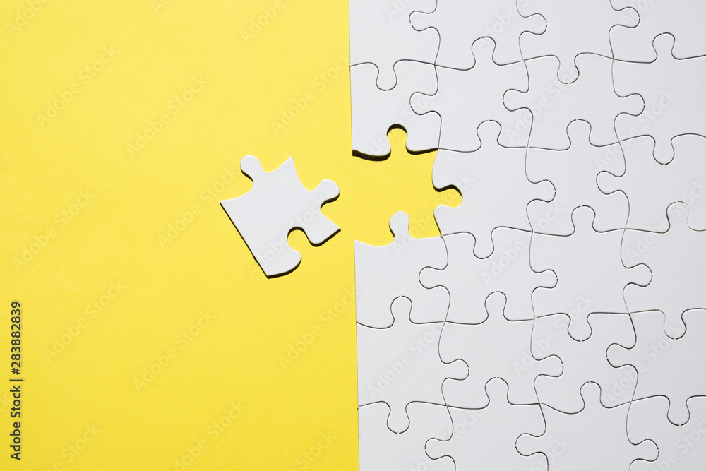 Fototapeta premium Set of white jigsaw puzzle pieces over yellow backdrop