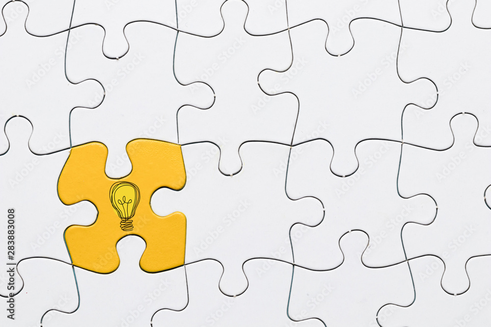Idea icon on yellow puzzle piece connected with white grid puzzle backdrop Idea icon on yellow puzzle piece connected with white grid puzzle backdrop