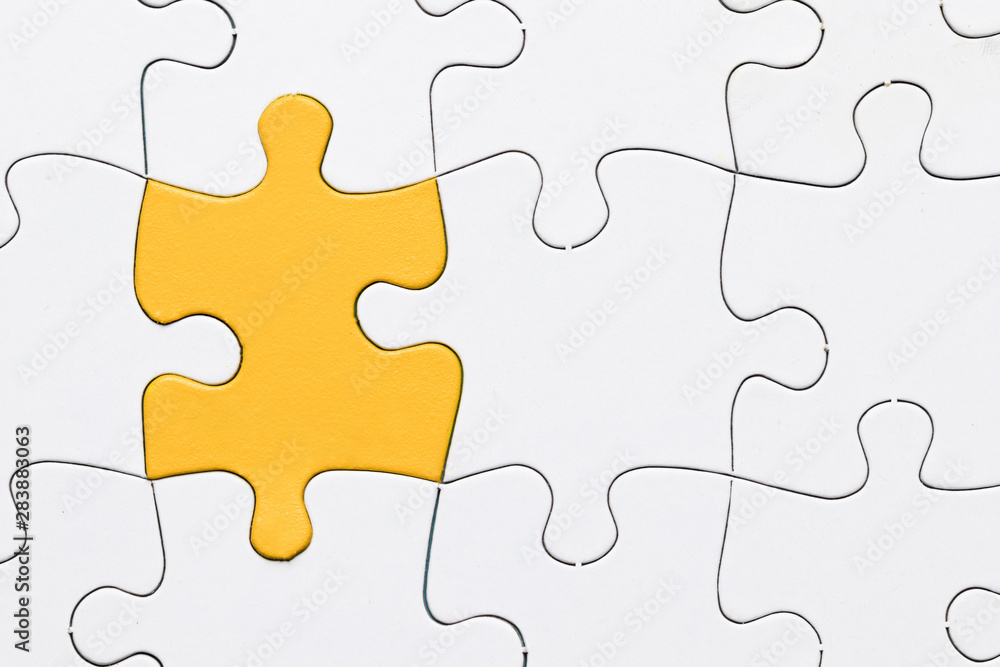 An overhead view of yellow puzzle among white piece An overhead view of yellow puzzle among white piece