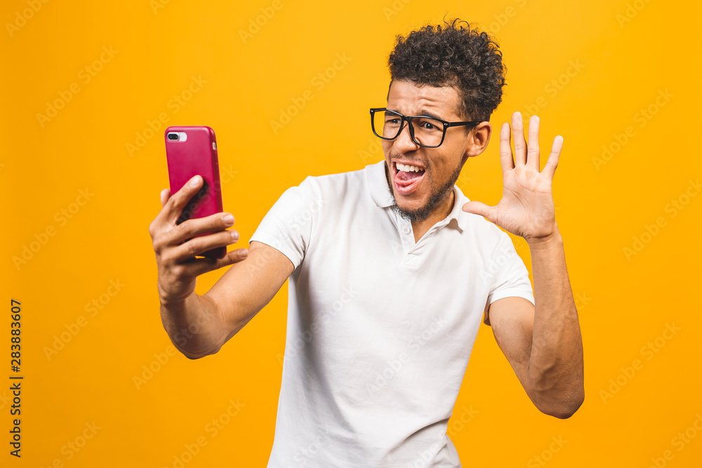 Image of happy young african american man posing isolated over yellow background take a selfie by phone. Image of happy young african american man posing isolated over yellow background take a selfie by phone.