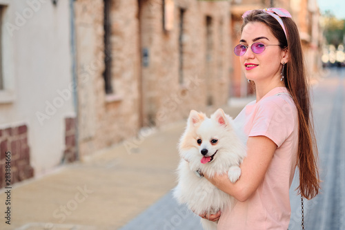 Portrait of a young girl walking with a white fluffy pomeranian.