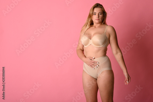 attractive chubby girl in underwear on pink background