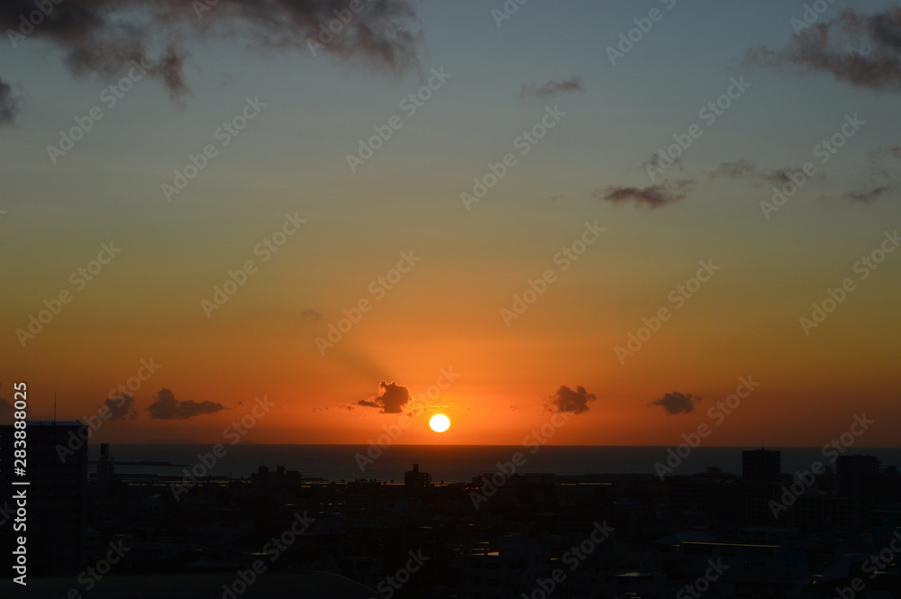 Fototapeta premium 水平線に沈む夕日と都会のシルエット