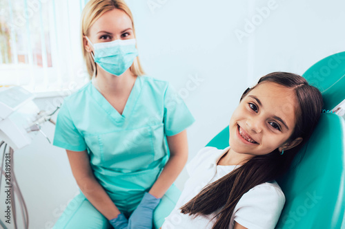 Fototapeta Naklejka Na Ścianę i Meble -  mixed race little girl visiting dentist. She sitting in dental chair in dental clinic. Child teeth exam .