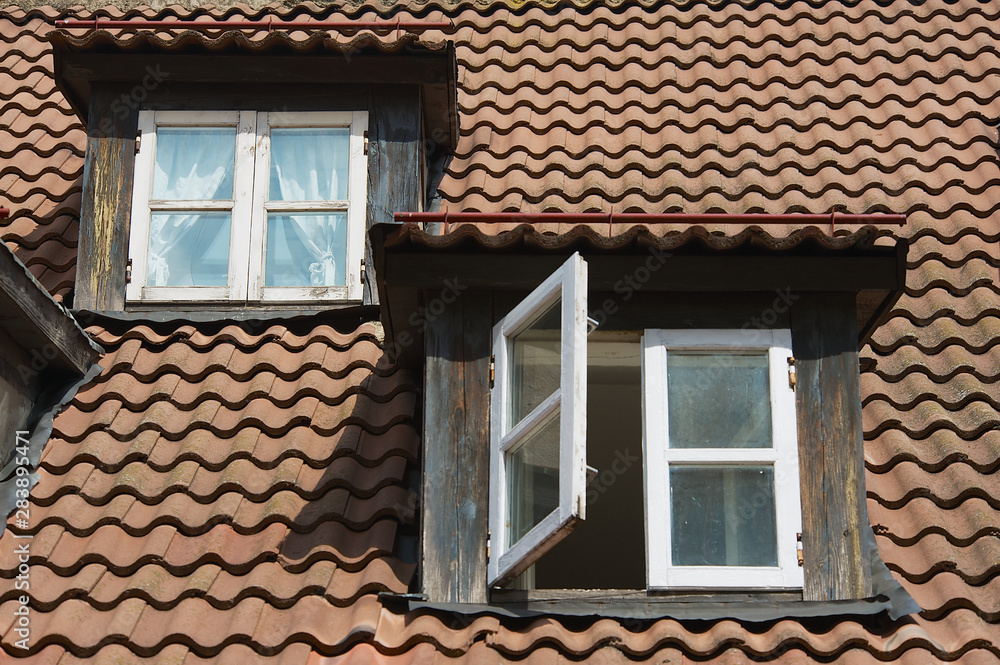 Vintage windows at the attic roof with brown tiles in the historical part of Riga, Latvia.