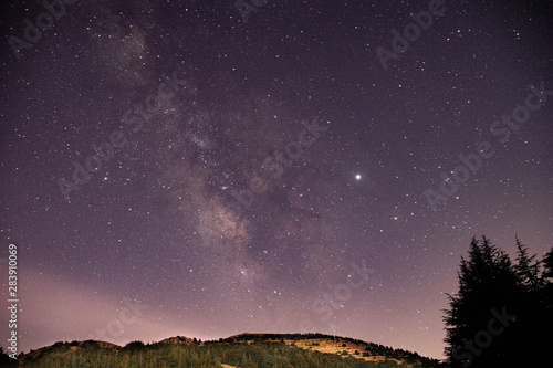 Beautiful clear night landscape and scenery. Starry sky with milky way galaxy over the mountains and the cedar trees.