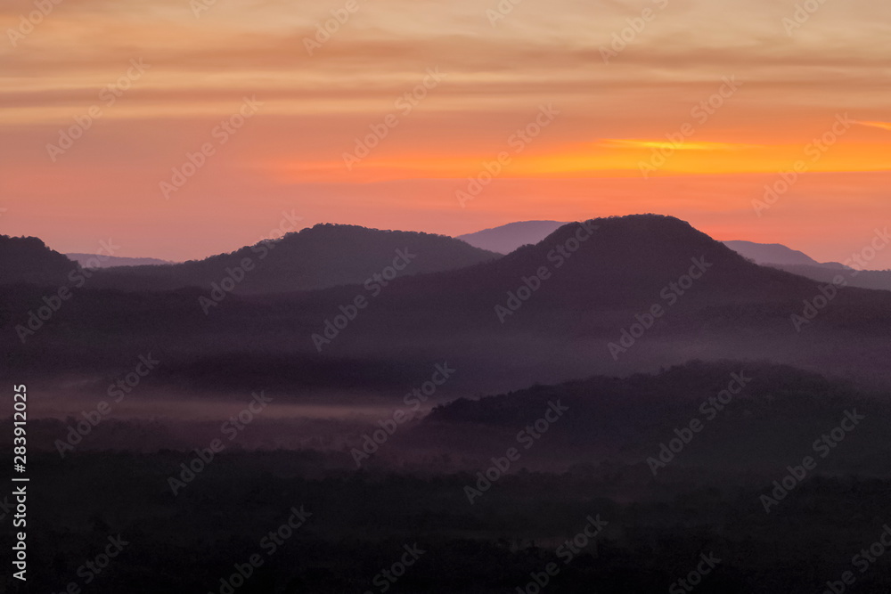 Mountain view morning of Peak mountain above Mekong river around with soft mist and red sun light in the sky background, sunrise at Cha Na Dai Cliff, Pha Taem National Park, Ubon Ratchathani, Thailand