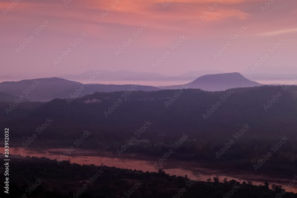 Top view above Mekong river around with mountains, forest, soft mist with red sky background, sunrise at Cha Na Dai Cliff, Pha Taem National Park, Ubon Ratchathani, Thailand.