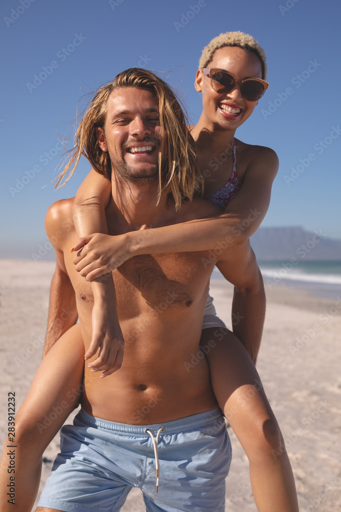 Man giving piggyback ride to woman on the beach Man giving piggyback ride to woman on the beach
