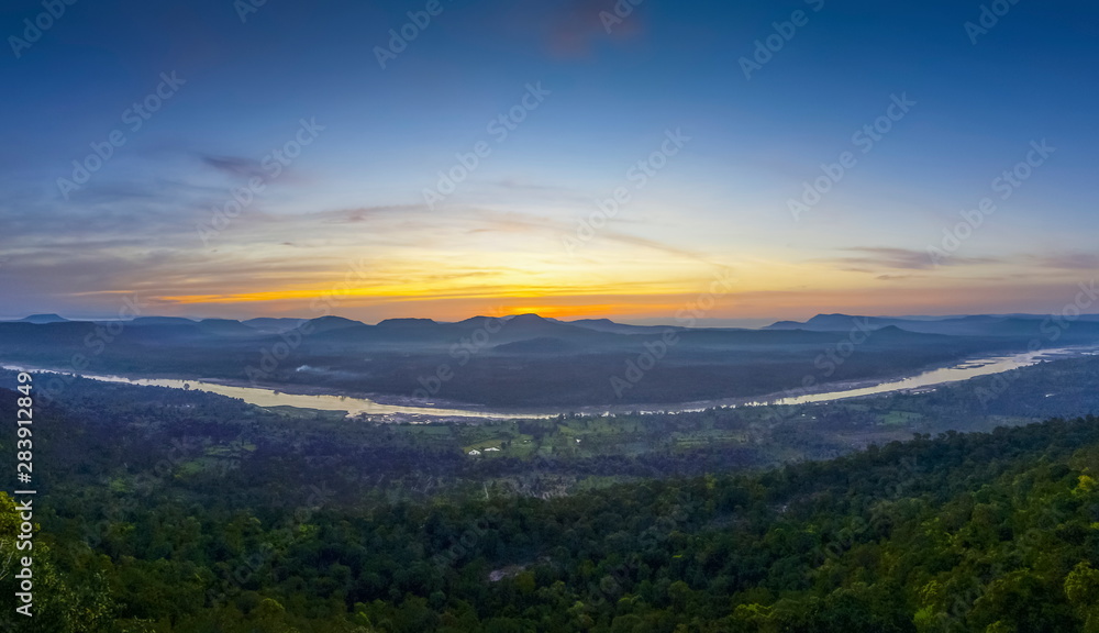 Top view panorama of Mekong river around with soft mist, forest, mountains with cloudy and yellow sun light in the sky background, sunrise at Cha Na Dai Cliff, Ubon Ratchathani, Thailand.
