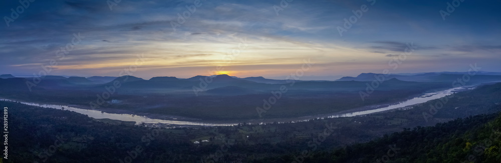 Top view panorama of Mekong river around with soft mist, forest, mountains with cloudy and yellow sun light in the sky background, sunrise at Cha Na Dai Cliff, Ubon Ratchathani, Thailand. Top view panorama of Mekong river around with soft mist, forest, mountains with cloudy and yellow sun light in the sky background, sunrise at Cha Na Dai Cliff, Ubon Ratchathani, Thailand.