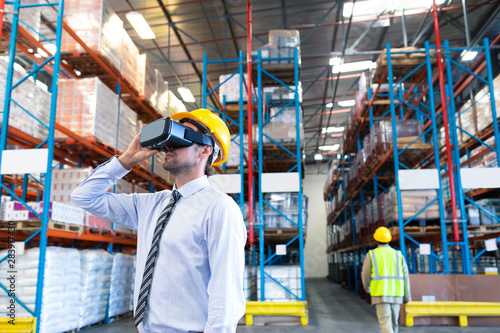 Male supervisor using virtual reality headset in warehouse