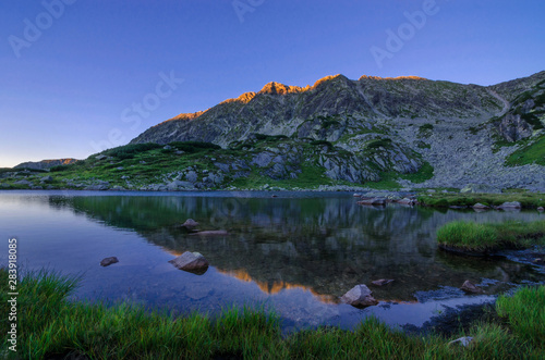 Mountain landscape and glacial Taul Portii lake in Retezat National Park, Carpathian Mountains, Romania, at sunrise