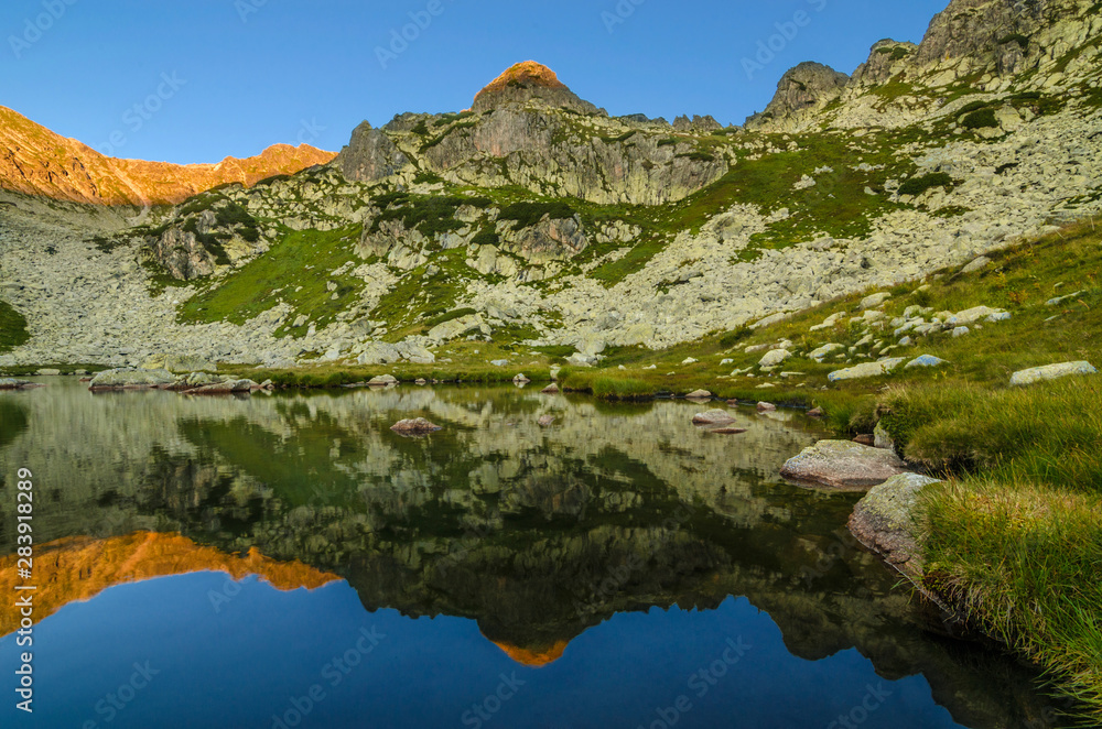Mountain landscape and glacial Taul Portii lake in Retezat National Park, Carpathian Mountains, Romania, at sunrise Mountain landscape and glacial Taul Portii lake in Retezat National Park, Carpathian Mountains, Romania, at sunrise