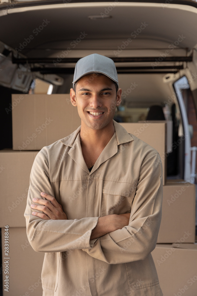 Delivery man standing with arms crossed near van outside the warehouse Delivery man standing with arms crossed near van outside the warehouse