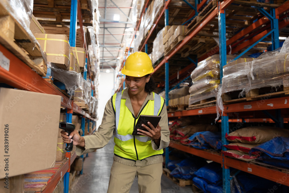 Female worker scanning package with barcode scanner while using digital tablet in warehouse Female worker scanning package with barcode scanner while using digital tablet in warehouse