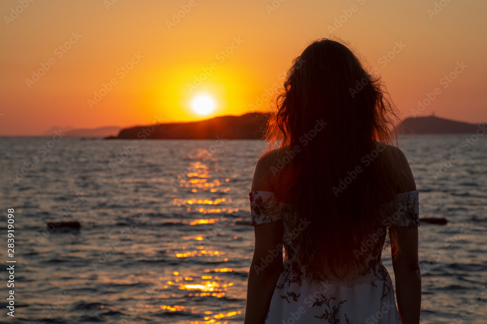 Girl on pontoon pier at sunset . Woman relaxing on pier looking at sea view at sunset