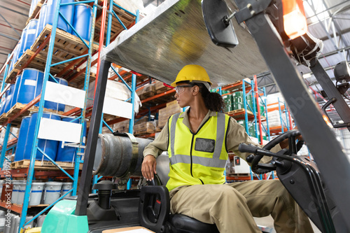 Female staff driving forklift in warehouse
