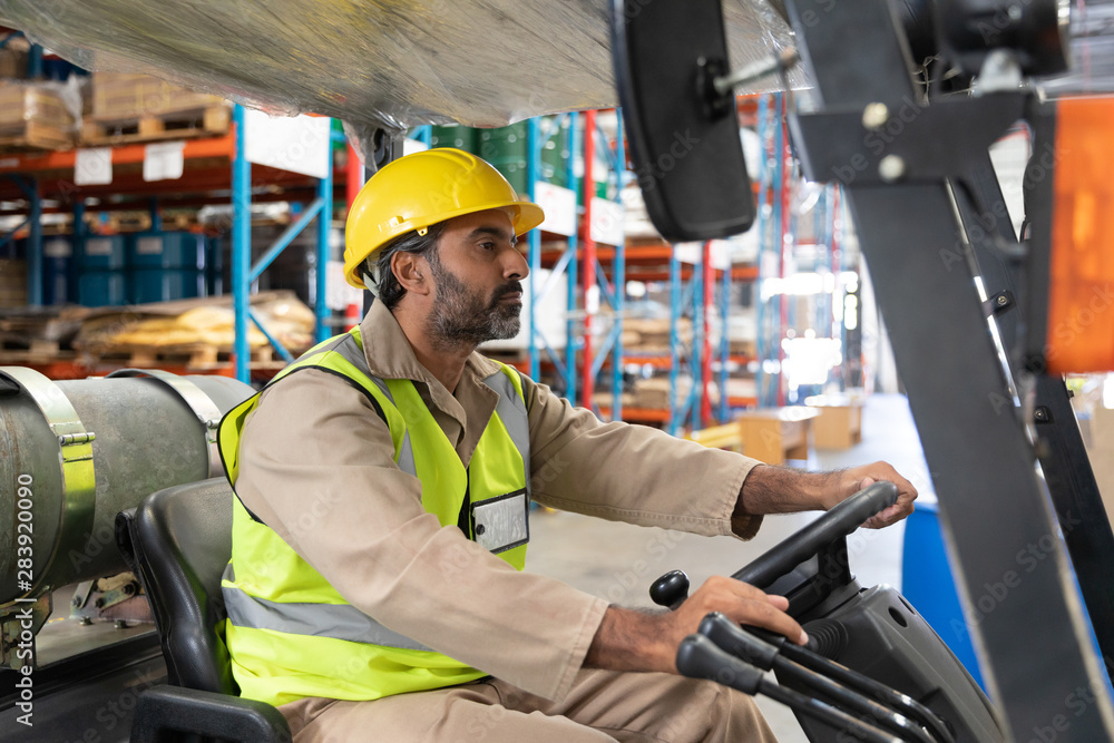 Male staff driving forklift in warehouse Male staff driving forklift in warehouse