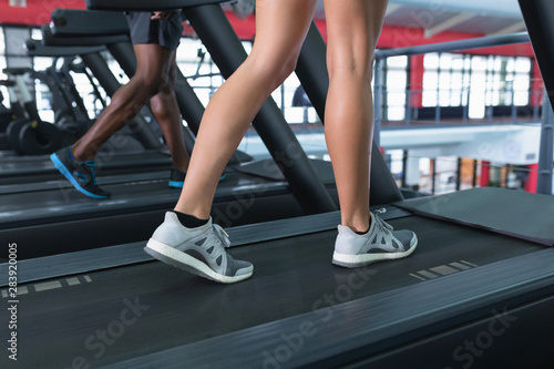 Low section of fit people exercising on treadmill
