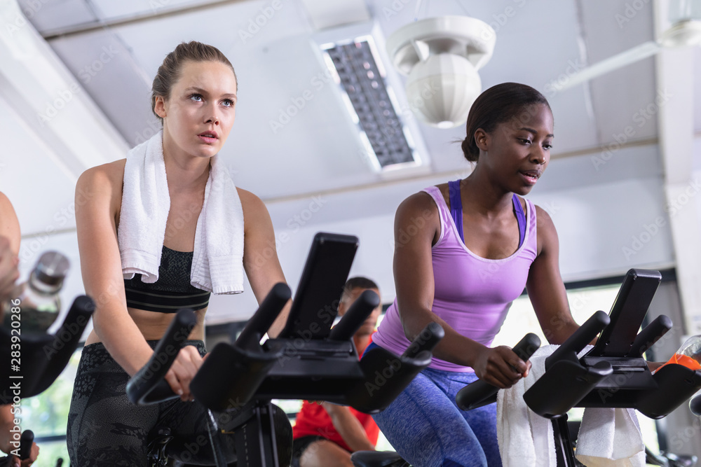 Fit women exercising on exercise bike in fitness center