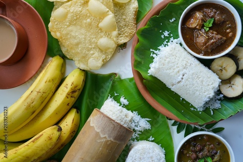 Kerala breakfast rice Puttu /Pittu made in bamboo mould served with Kadala curry banana papad and tea on banana leaf photo