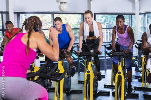 Female trainer training people to work out on exercise bike