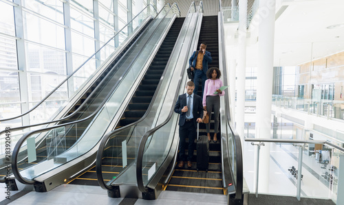 Diverse business travellers coming down an escalator photo