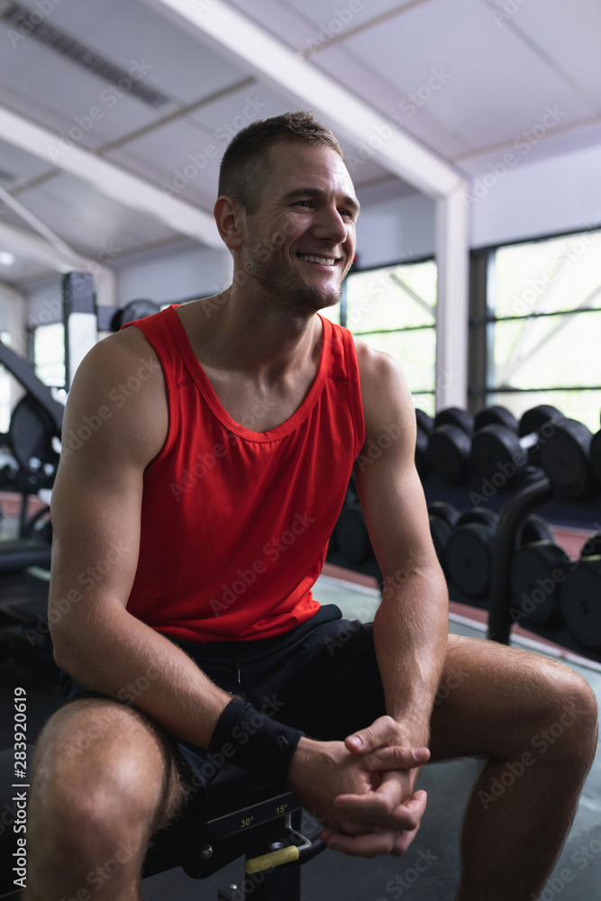 Happy man looking away while sitting in fitness center Happy man looking away while sitting in fitness center