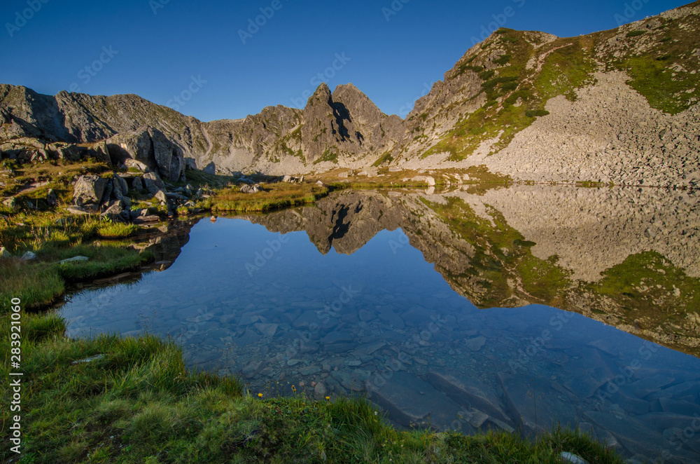 Mountain landscape and glacial Taul Portii lake in Retezat National Park, Carpathian Mountains, Romania, at sunrise Mountain landscape and glacial Taul Portii lake in Retezat National Park, Carpathian Mountains, Romania, at sunrise