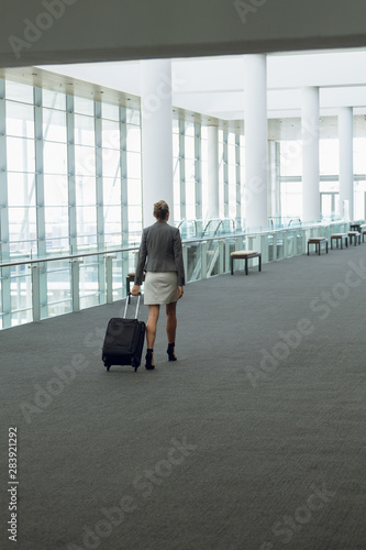 Businesswoman walking with luggage in the corridor at office