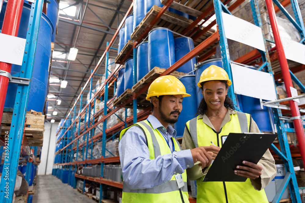 Male and female worker discussing on clipboard in warehouse Male and female worker discussing on clipboard in warehouse