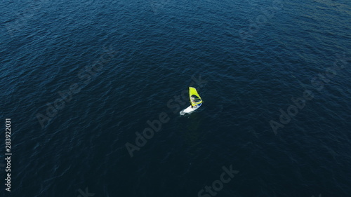 Windsurf woman alone in the blue sea. Windsurfing on the surface of the water