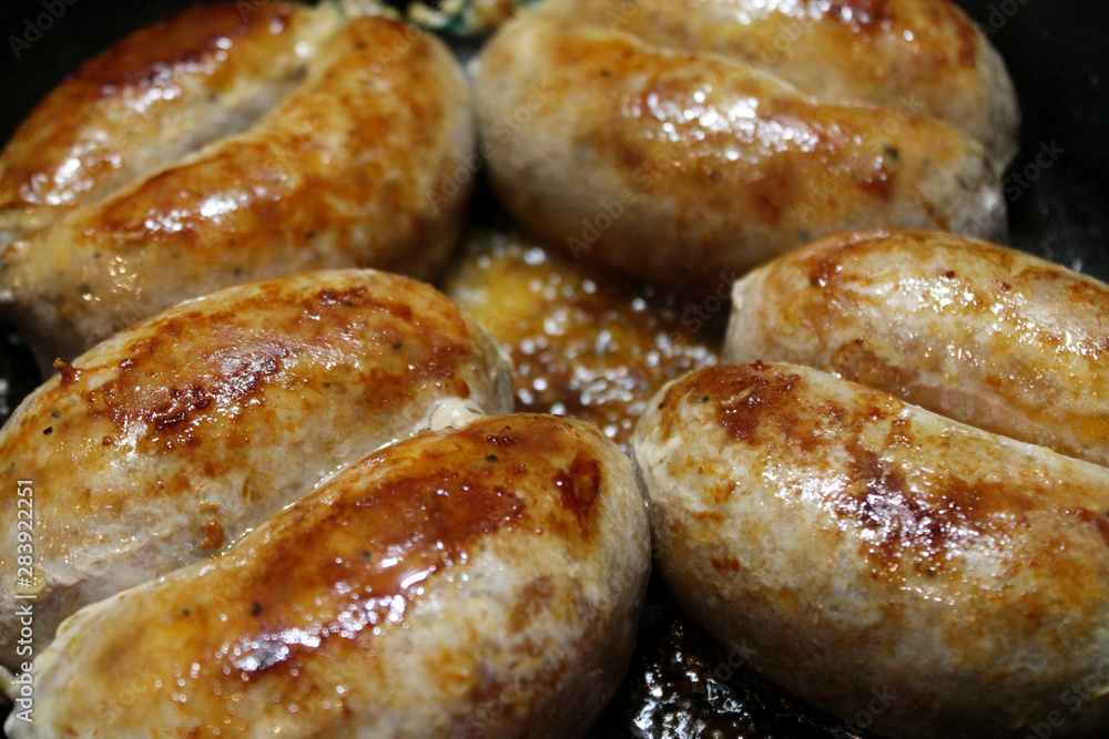 Browned sausages frying on the pan. Octoberfest cuisine objects. Food photography. Juicy and succulent frankfurters. Tasty and appetizing franks