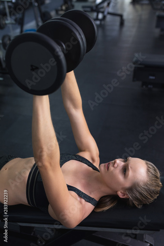 Woman exercising with dumbbell in fitness center