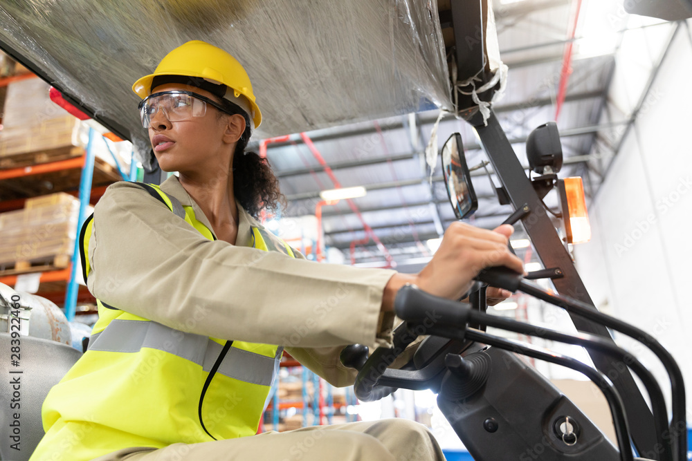 Female staff driving forklift in warehouse Female staff driving forklift in warehouse