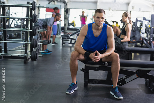 Fit man relaxing on a bench in fitness center