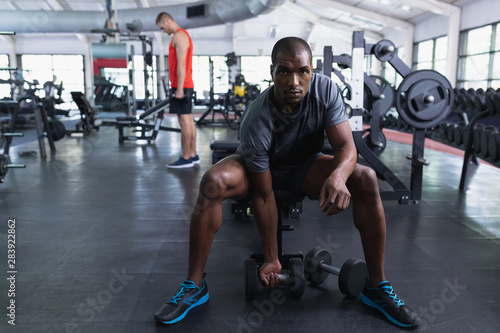 Fit man exercising with dumbbells in fitness center