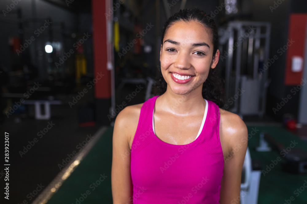 Female athletic looking at camera while standing in fitness center