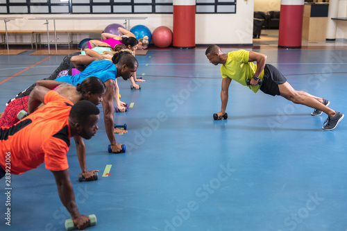 Male trainer training people to exercise with dumbbells