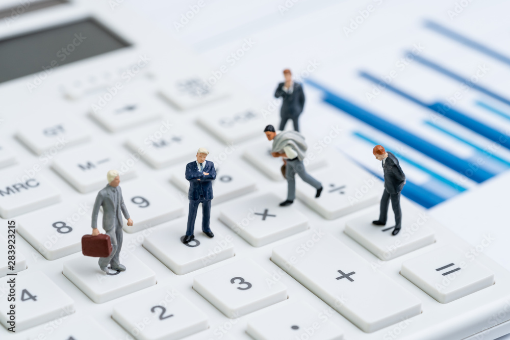 Mutual funds, business performance success, profit and loss in accounting or company management concept, miniature people figurine businessmen standing on calculator with bar graph and chart reports Mutual funds, business performance success, profit and loss in accounting or company management concept, miniature people figurine businessmen standing on calculator with bar graph and chart reports