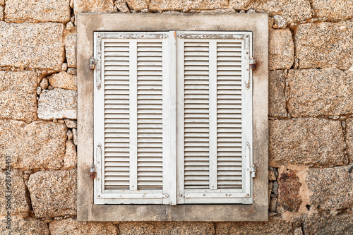 Window with closed white wooden shutters