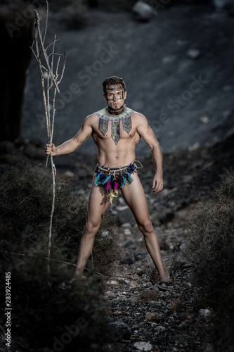 Handsome male in loincloth standing with stick