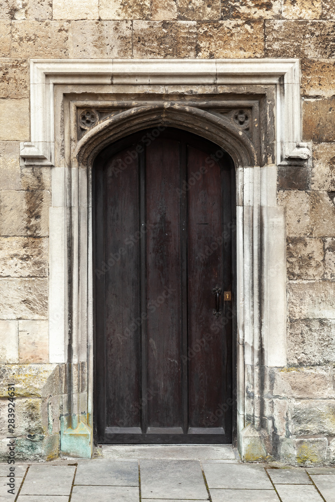 Closed black wooden door in old stone wall