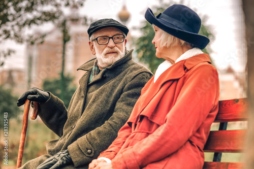 Elderly couple sitting on bench looking at each other