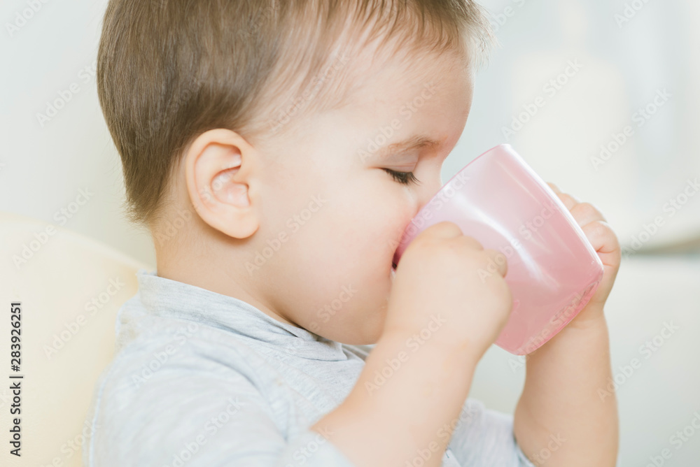 child in the kitchen drinking from a cup of water